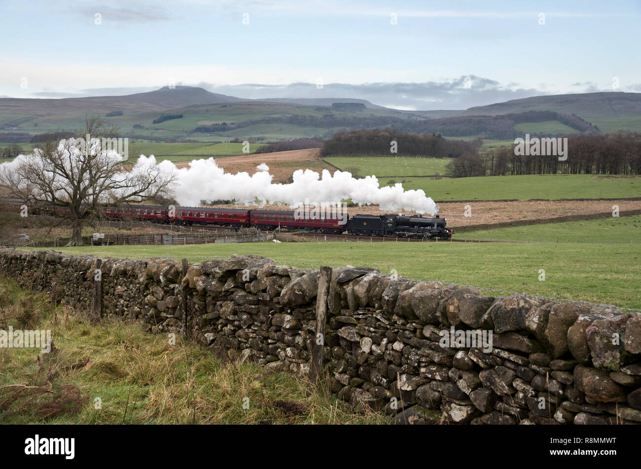 Clapham Moor, North Yorkshire, UK. 16th Dec 2018. Santa Special steam train from Lancaster to Carnforth via Hellifield. Seen here at Clapham Moor near Settle, North Yorkshire. Ingleborough peak in on the horizon. The locomotive is a 1940s Stanier 8F. Credit: John Bentley/Alamy Live News Stock Photo