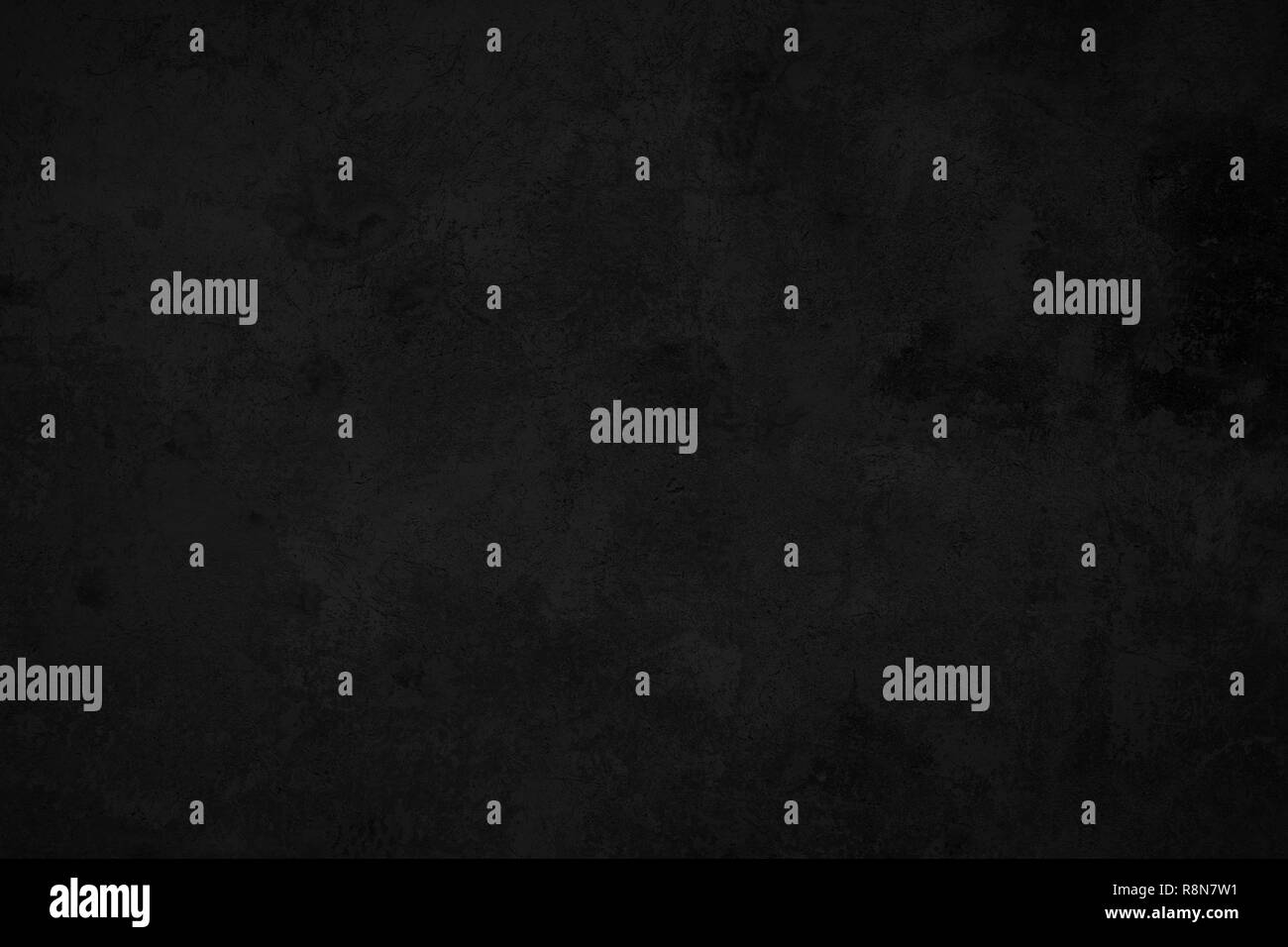 Closeup of a weathered and aged dark gray, almost black, concrete wall