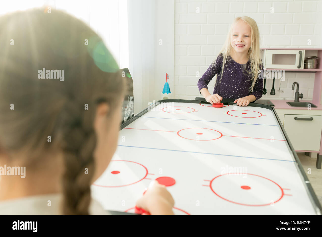 Positive little girls having fun in games room Stock Photo