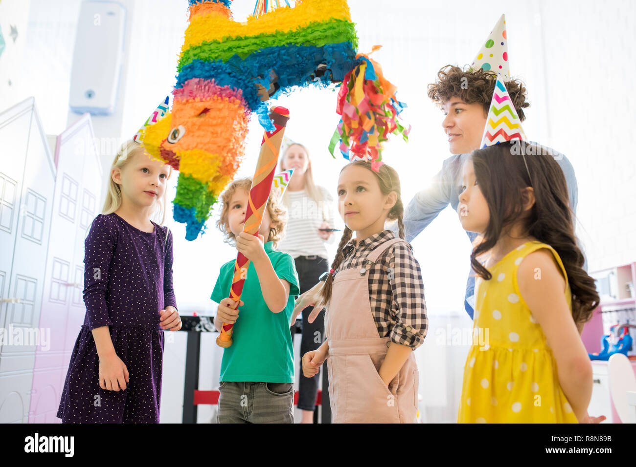 Curious children standing around pinata Stock Photo