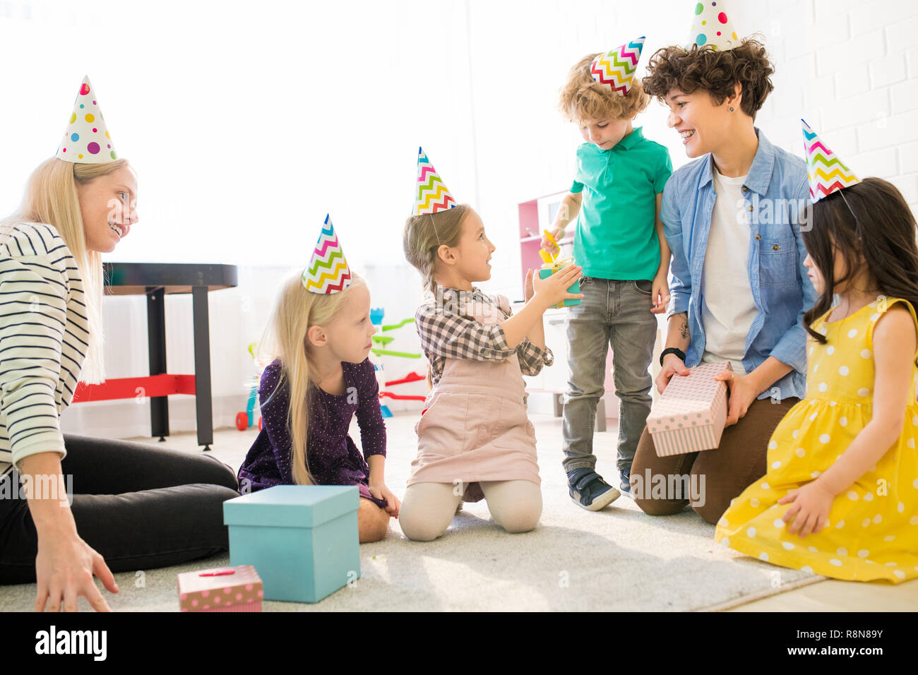 Young mothers playing with kids at birthday party Stock Photo