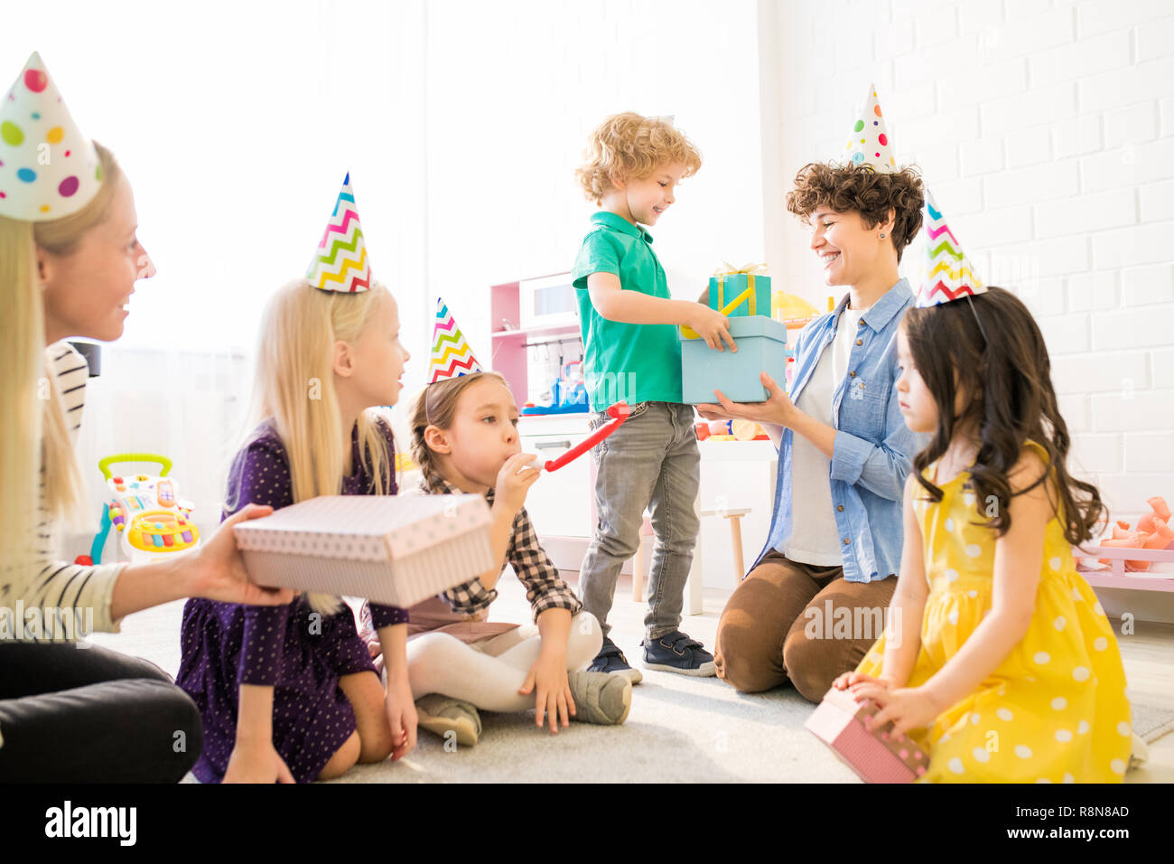 Cute boy giving gift boxes to mother at birthday party Stock Photo