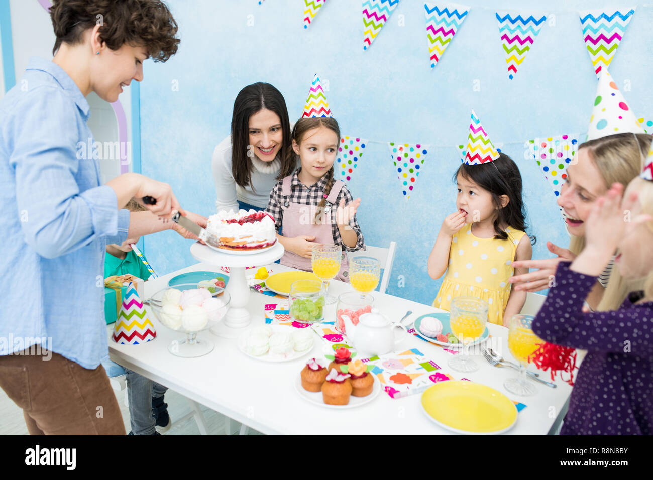 Mother cutting cake with knife for kids Stock Photo