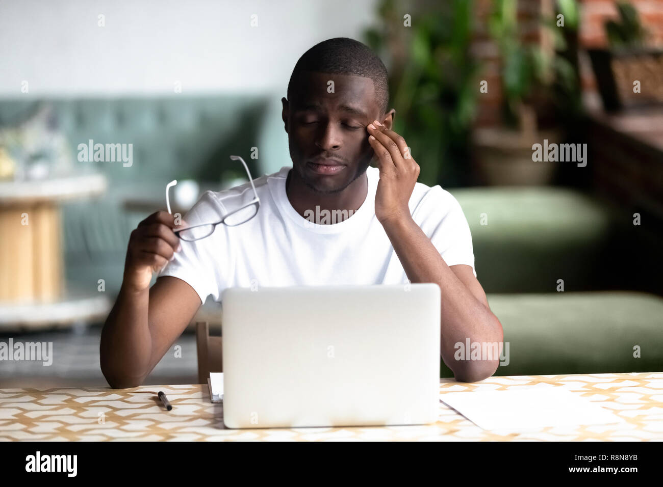 Tired African American man taking off glasses, feel eye strain Stock