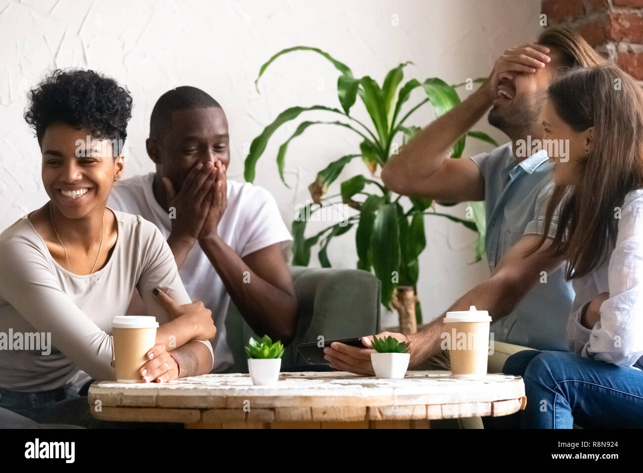 Diverse excited friends having fun together in cafe Stock Photo