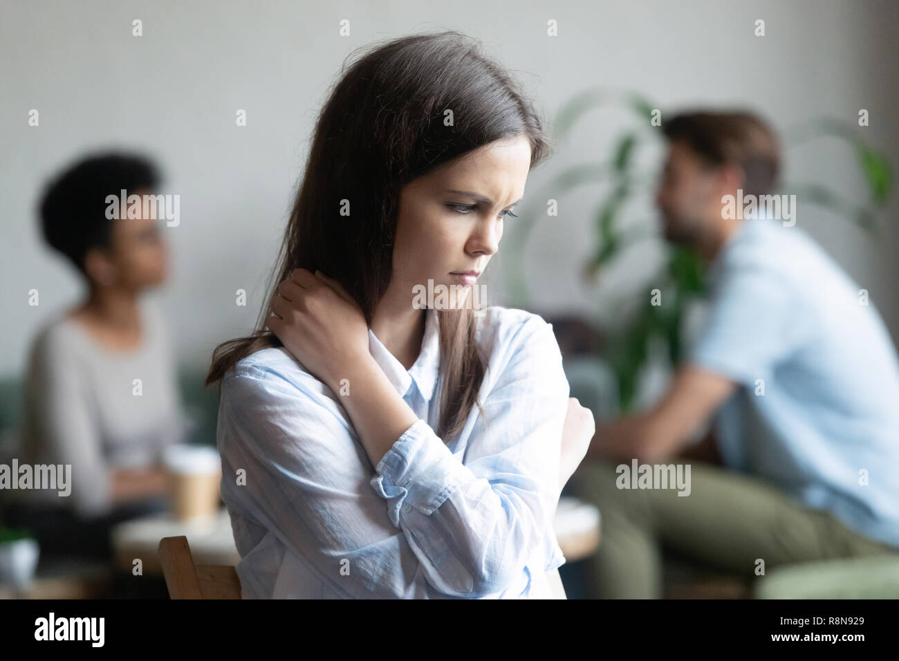 Upset young woman sitting alone in cafe offended at friends Stock Photo
