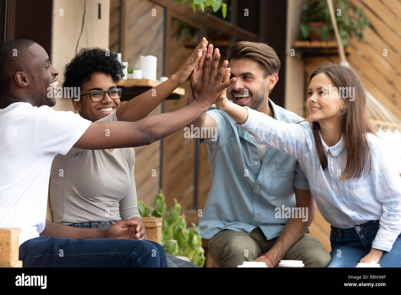 Happy multiethnic friends giving high five, celebrate success Stock Photo