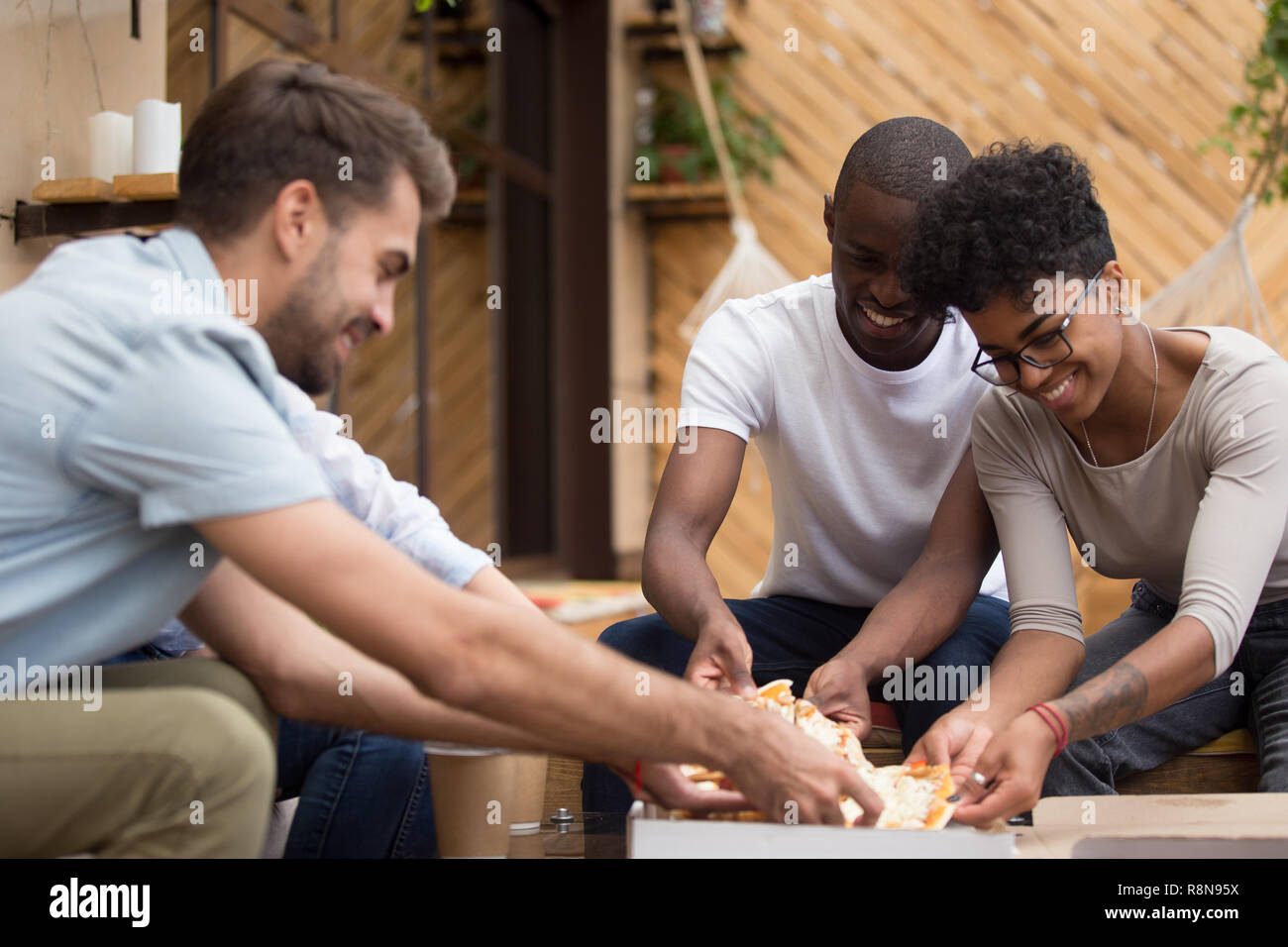 Smiling diverse multiethnic friends taking pizza slices from box Stock Photo