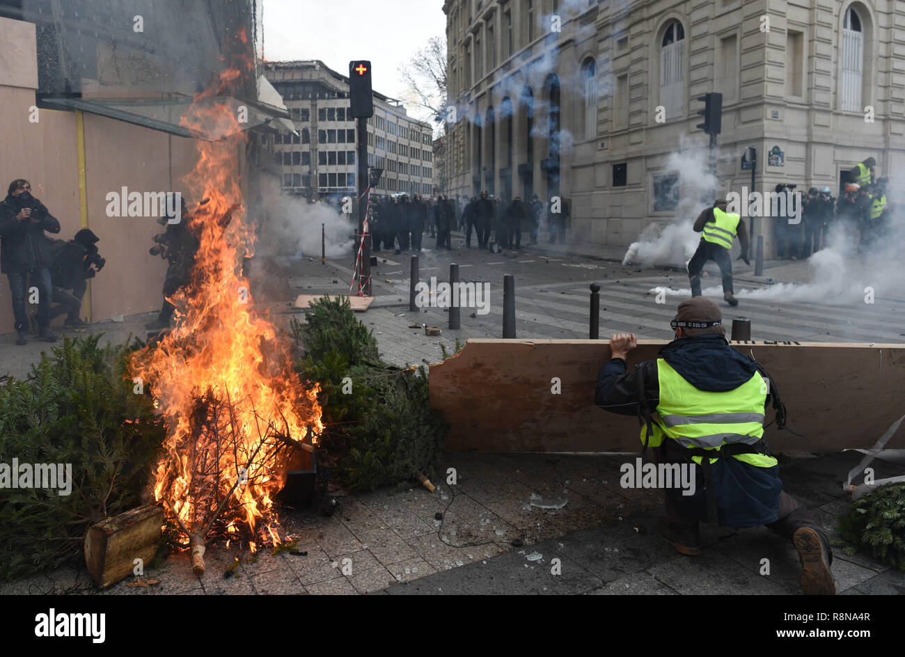 December 08, 2018 - Paris, France: Yellow Vests clash with French riot police near the Champs-Elysees avenue. Some protesters tried to build barricade with burning christmas trees before being tear gassed and dispersed by police.  Manifestation des Gilets Jaunes du 8 decembre a Paris, l'acte IV de leur mobilisation. *** FRANCE OUT / NO SALES TO FRENCH MEDIA *** Stock Photo
