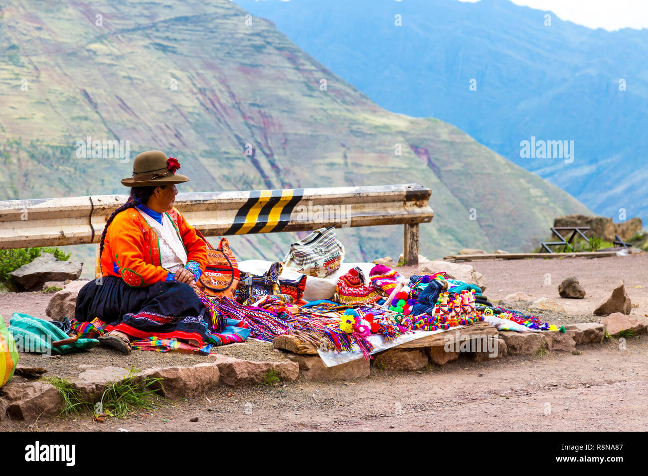Peruvian woman sitting on the ground selling souvenirs at Pisac, Sacred Valley, Peru Stock Photo