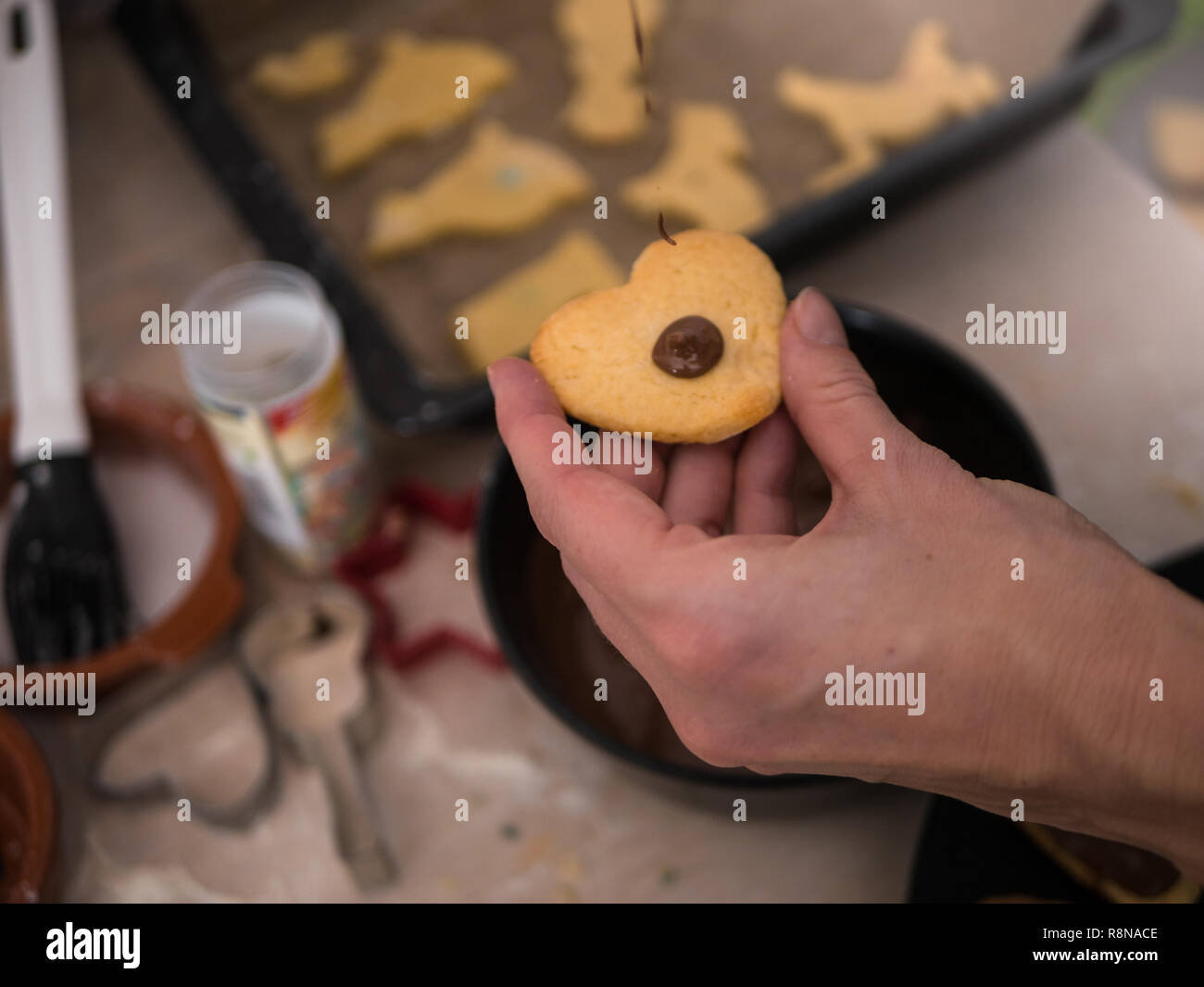 Christmas bakery: Woman pouring dark  chocolate onto a christmas cookie Stock Photo