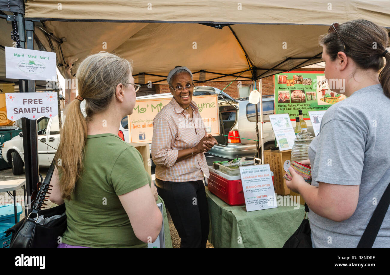 Lynn Porter, co-owner of Mo' Mint & Thyme, talks with customers about the company's all-natural drinks at the Farmers' Market in Tucker, Georgia. Stock Photo
