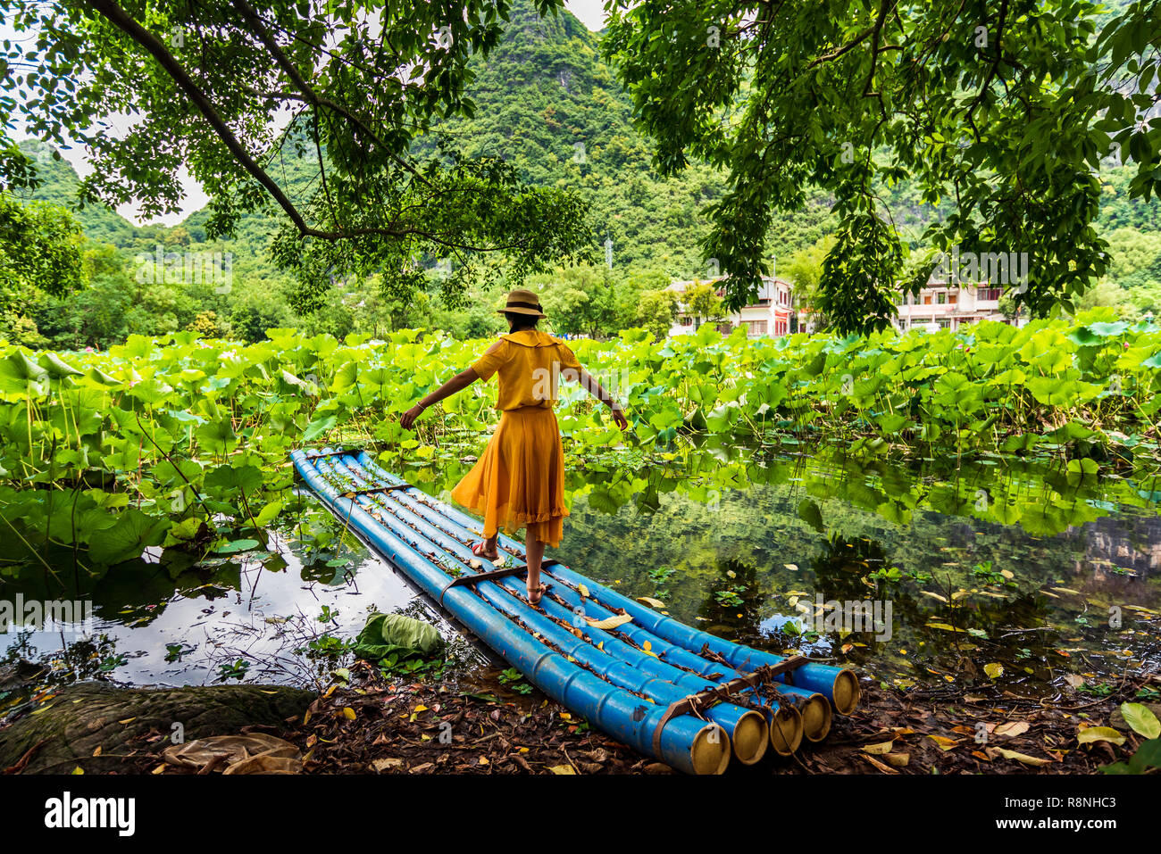 Girl standing on bamboo raft in lotus flower lake Stock Photo