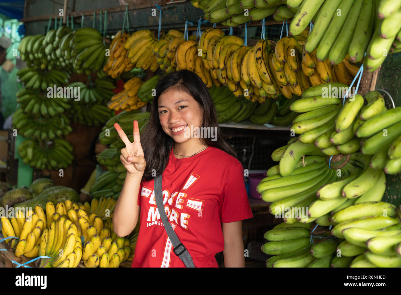 A young Filipina girl selling bananas smiles for the camera. Stock Photo