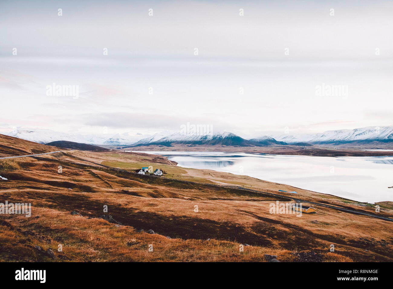 Village with farms in a rural area of the mountains of Iceland, with snowy mountains in the background. Stock Photo