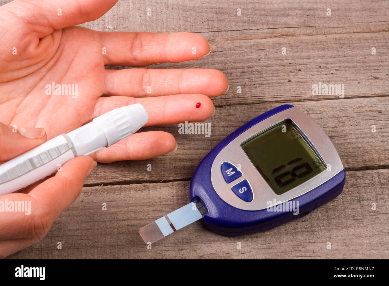 blood glucose meter with a hand on an old wooden background Stock Photo