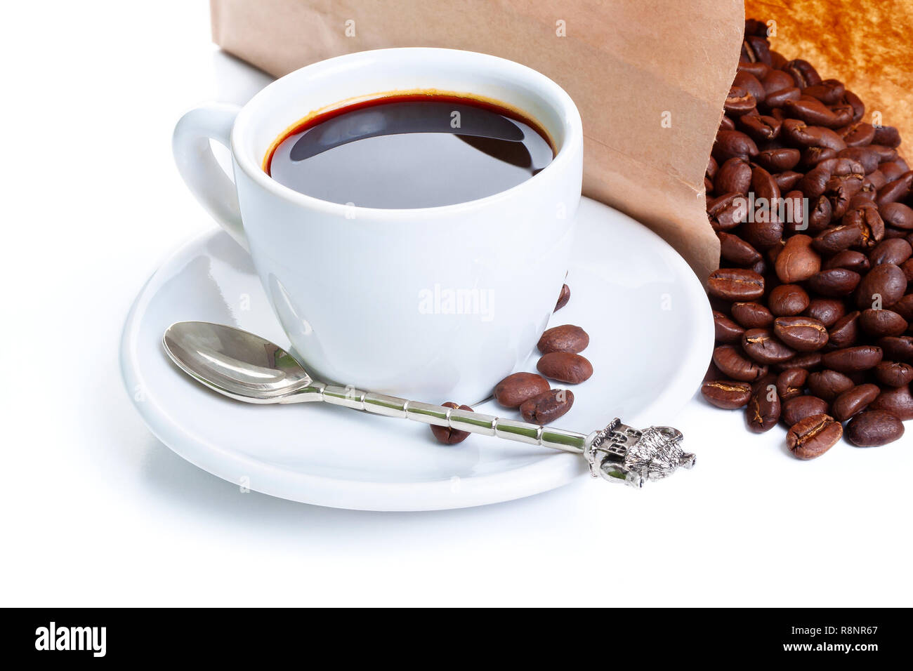 white cup of black coffee near the laying paper bag with coffee beans Stock Photo