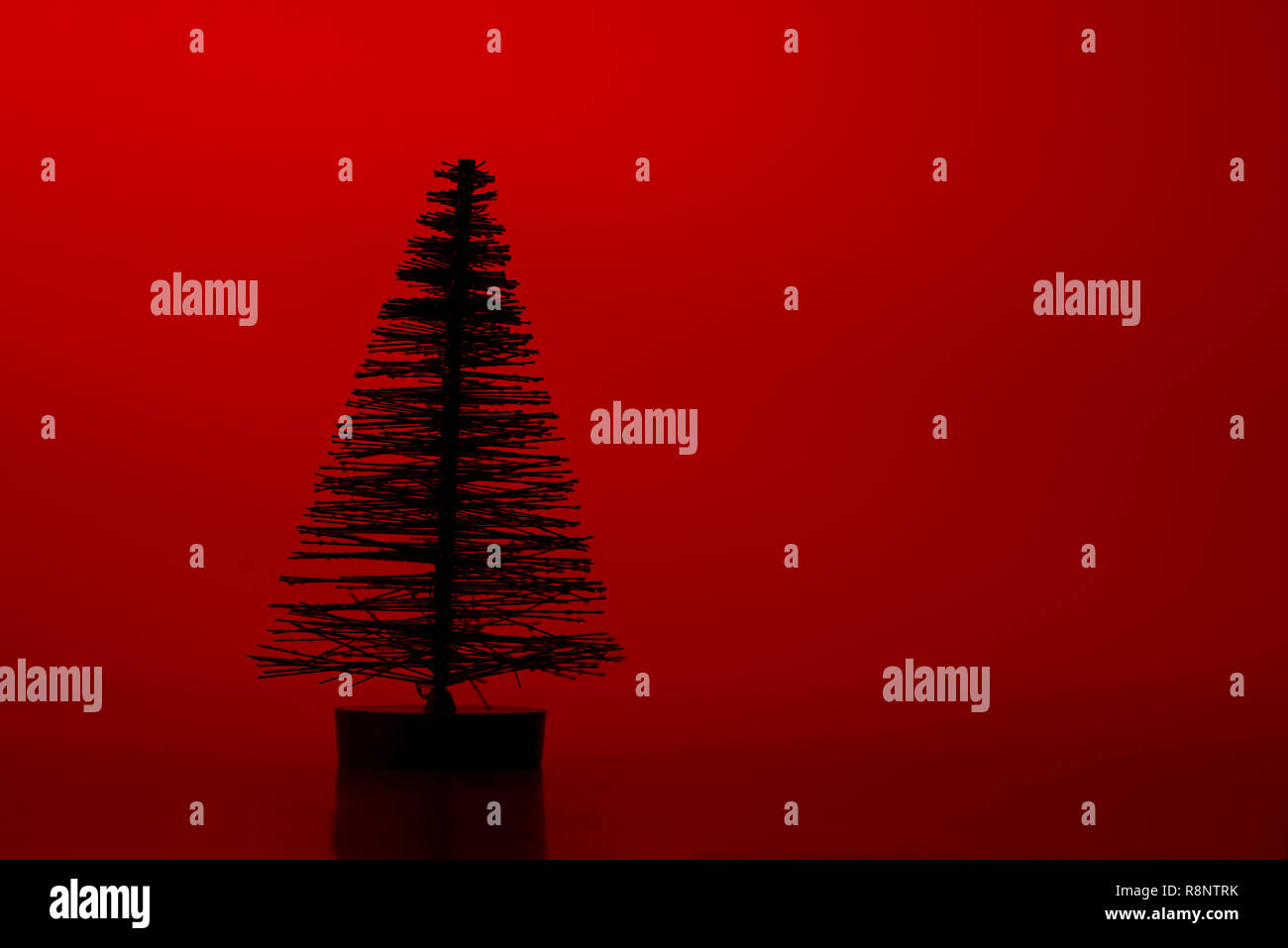 One silhouette artificial pine tree on a red background. Stock Photo
