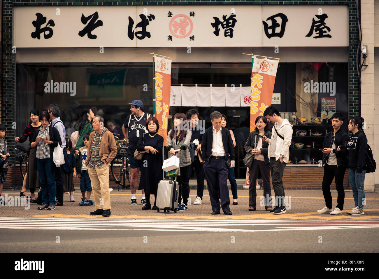 Japanese members of the public waiting to cross the road in the Shinjuku area of Tokyo Stock Photo