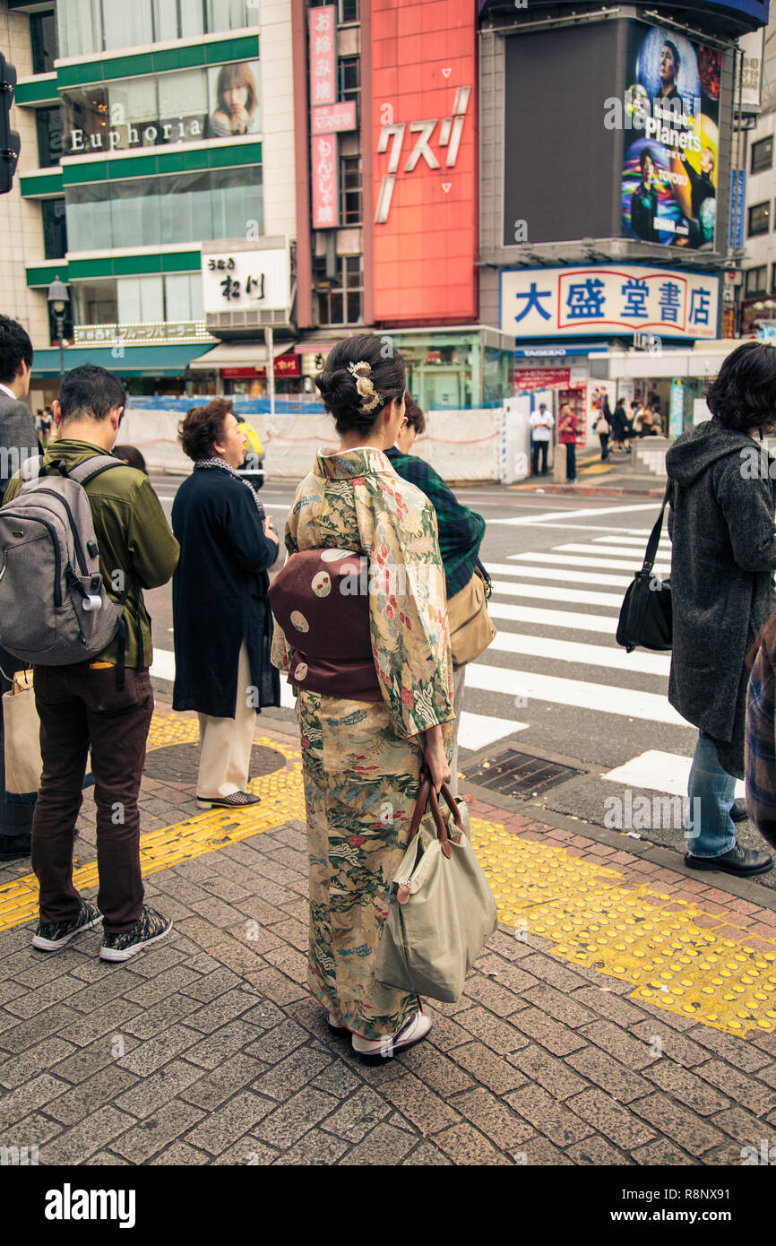 A Japanese woman in traditional kimono waits at the Shibuya crossing in ...
