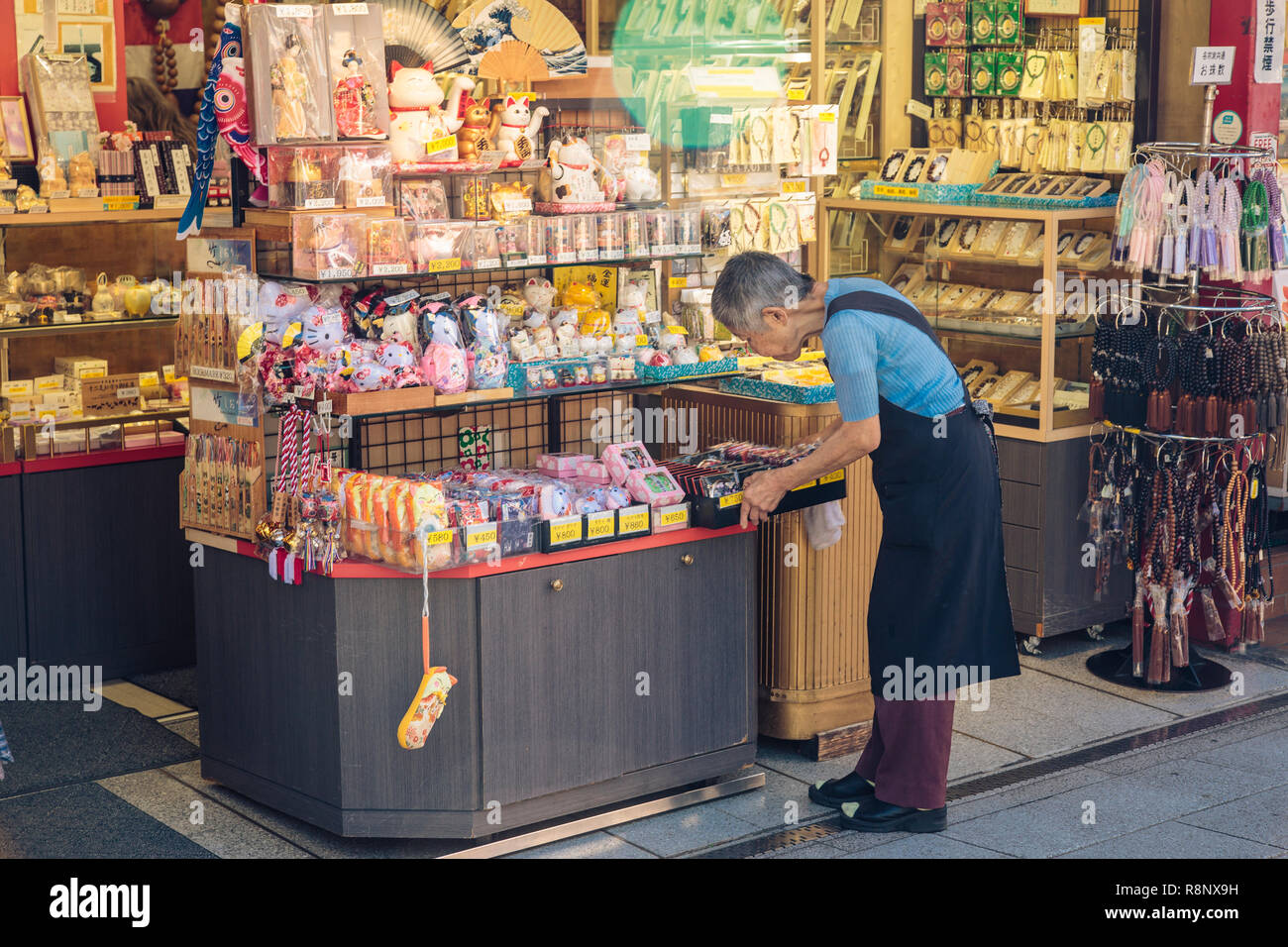 An elderly Japanese woman selling souvenirs on Nakamise-dōri near Sensō-ji in Tokyo,Japan. Stock Photo