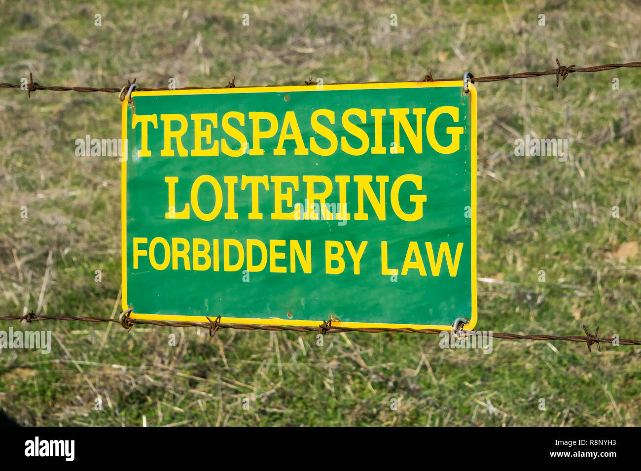"Trespassing Loitering Forbidden by Law" sign posted on a barbed wire