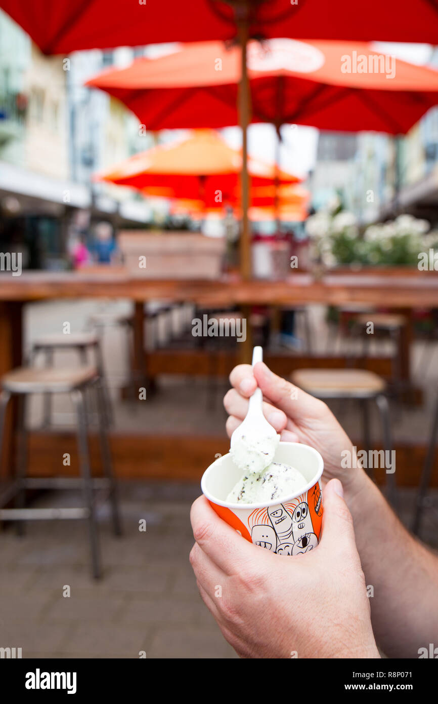 A tourist enjoys a tub of gelato in New Regent Street, Christchurch, New Zealand Stock Photo