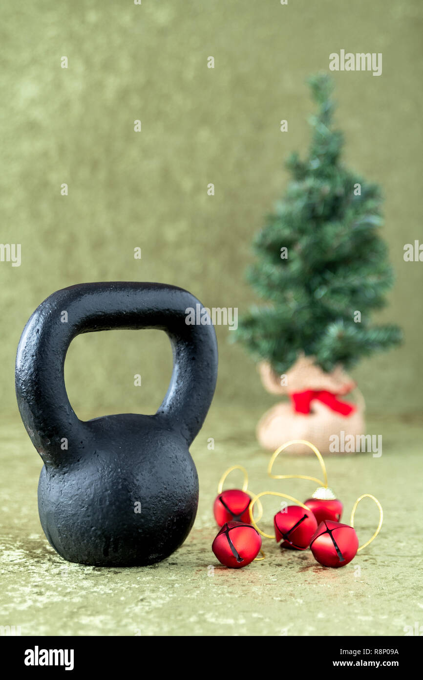 Black kettlebell on a green velvet background with red jingle bells on gold  thread, holiday fitness, Christmas tree in background Stock Photo - Alamy