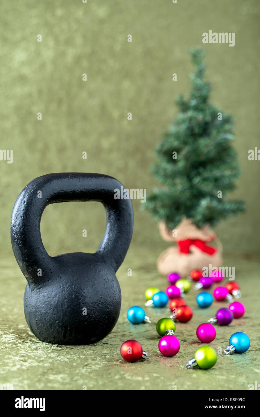 Black kettlebell on a green velvet background with colorful ball ornaments,  holiday fitness, Christmas tree in background Stock Photo - Alamy