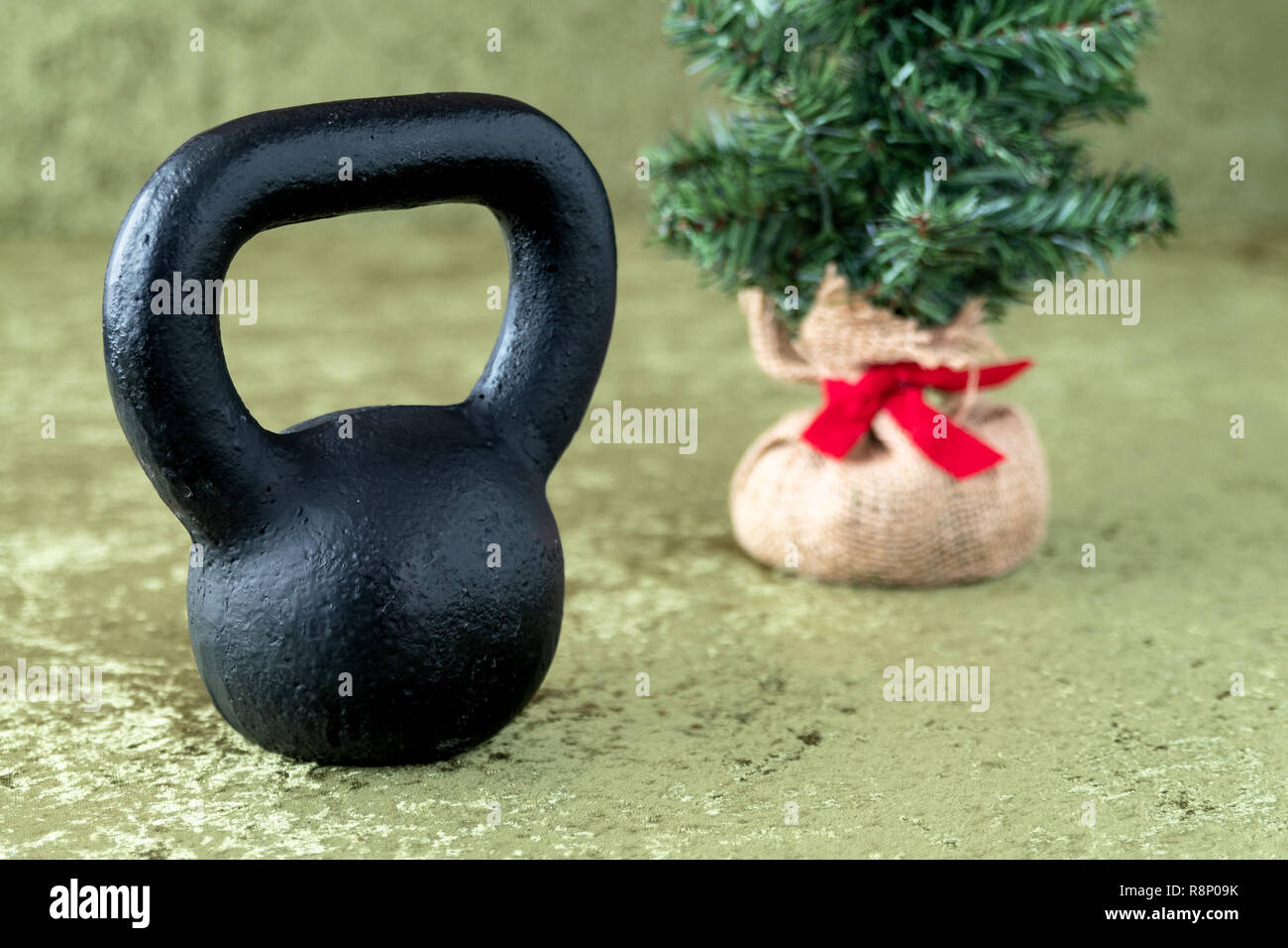 Black kettlebell on a green velvet background, holiday fitness, Christmas  tree in background Stock Photo - Alamy
