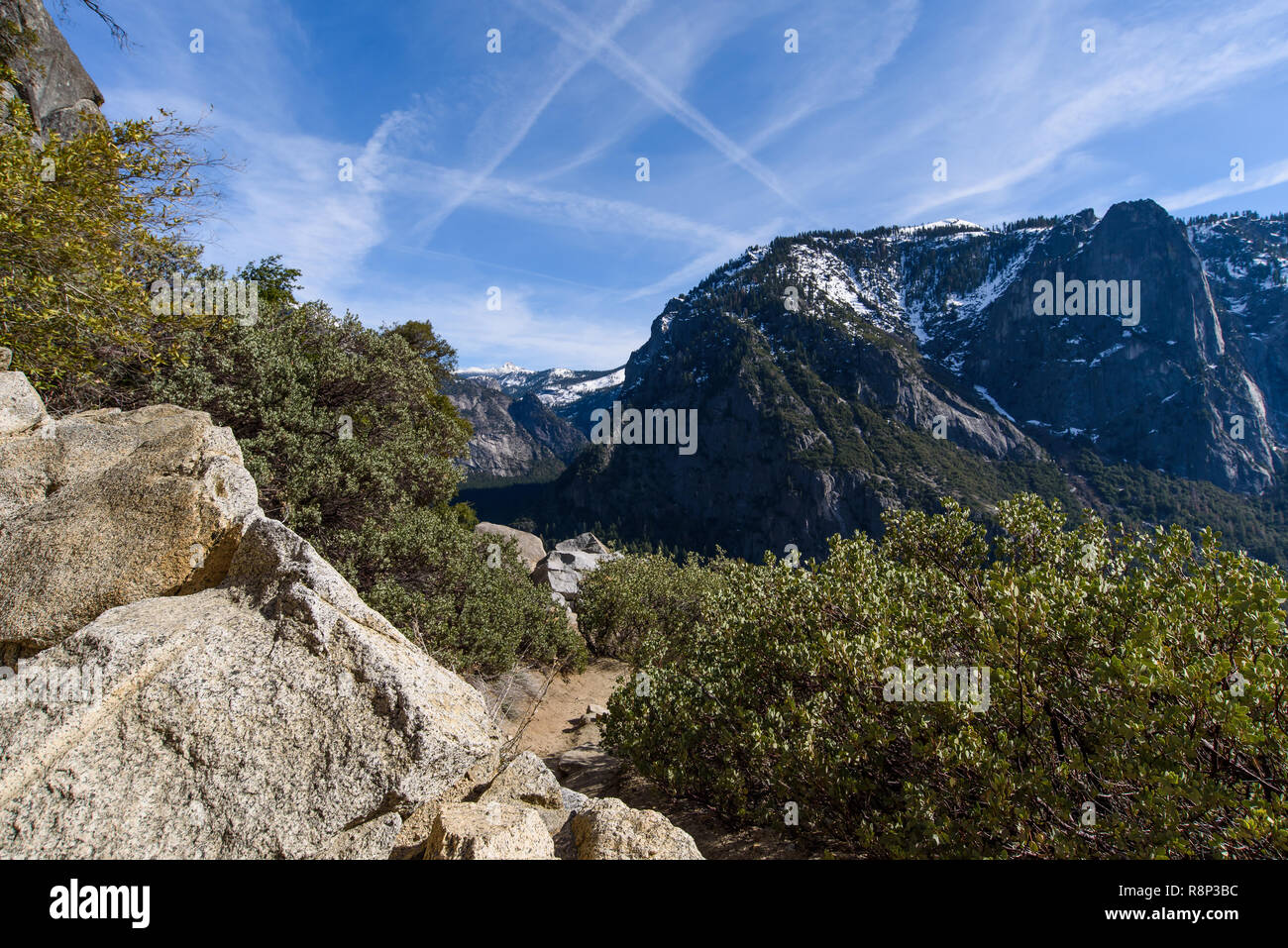 View of Half Dome, Yosemite National Park, set against blue sky streaked with vapour trails. Stock Photo