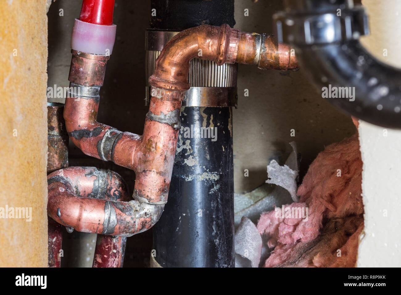 Close up detail of repaired plumbing pipes, drain and insulation inside residential wall. Stock Photo