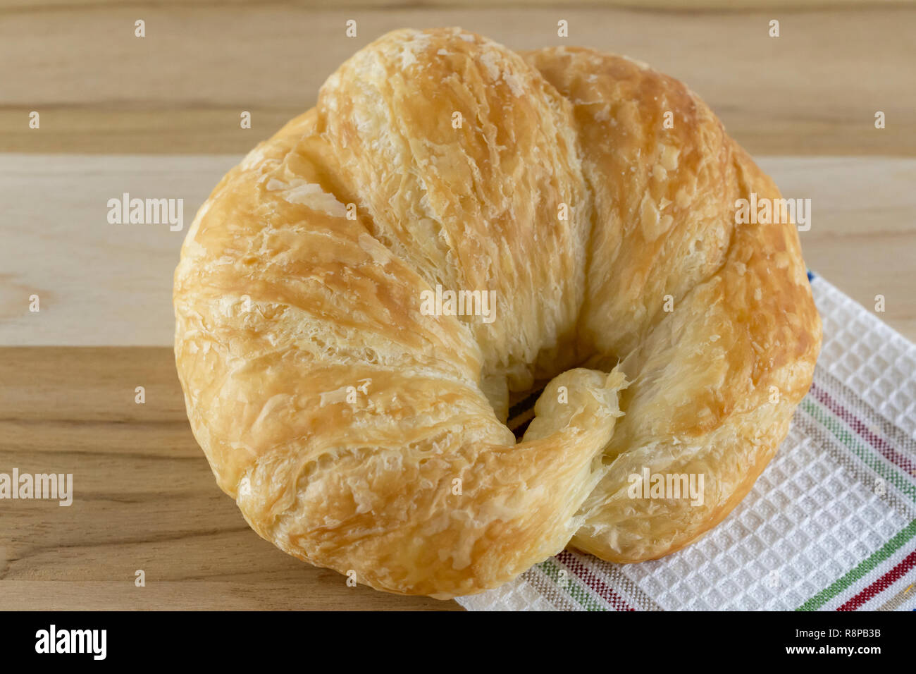 Single croissant on wooden board with cloth.  Top macro view. Stock Photo