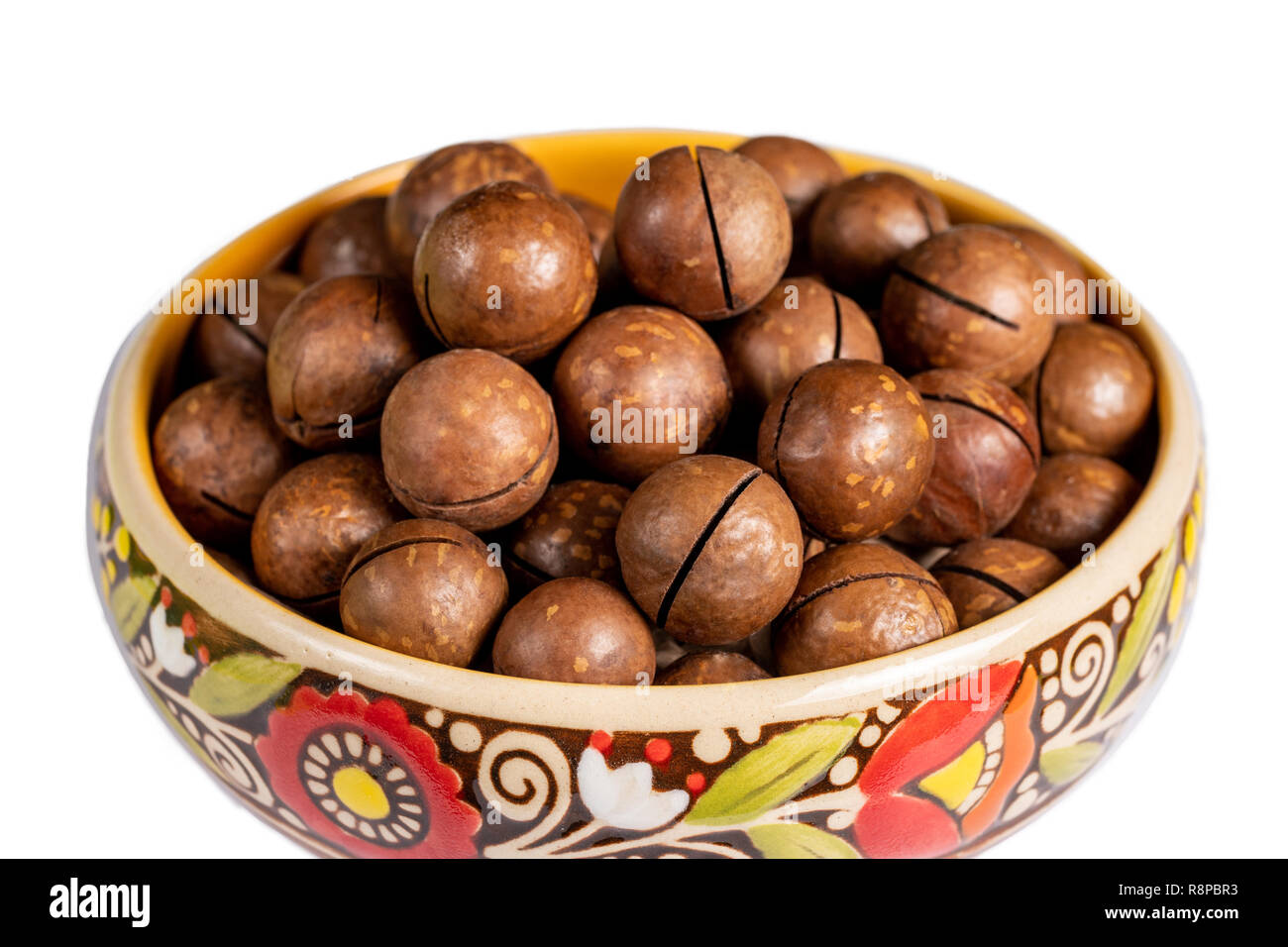 Fresh organic peeled macadamia nuts in ceramic bowl isolated on white