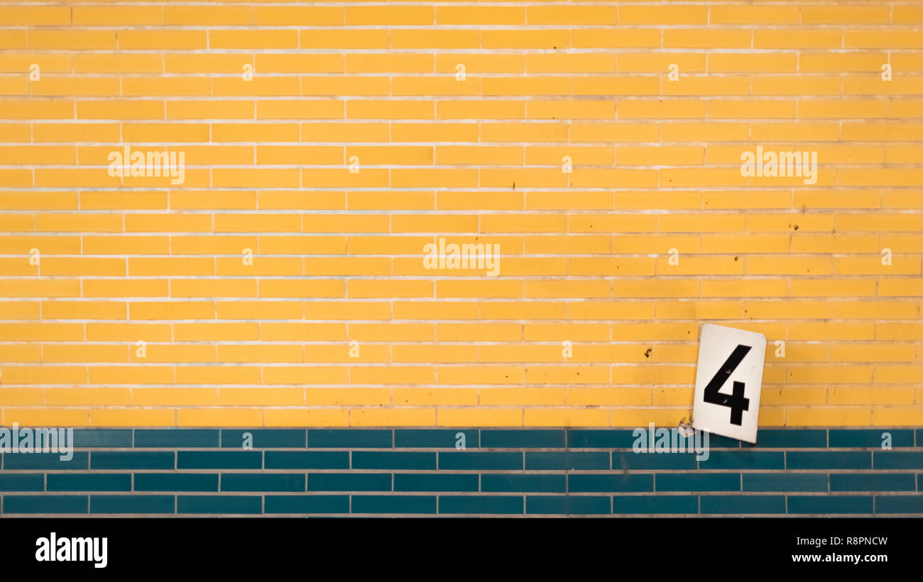 The sign number four on a tiled yellow wall Stock Photo - Alamy