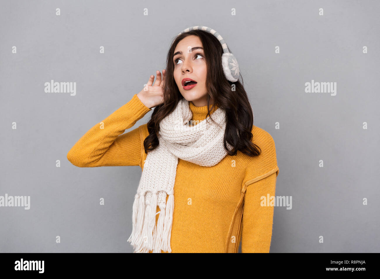 Portrait of european woman wearing ear muffs and scarf looking aside isolated over gray background Stock Photo