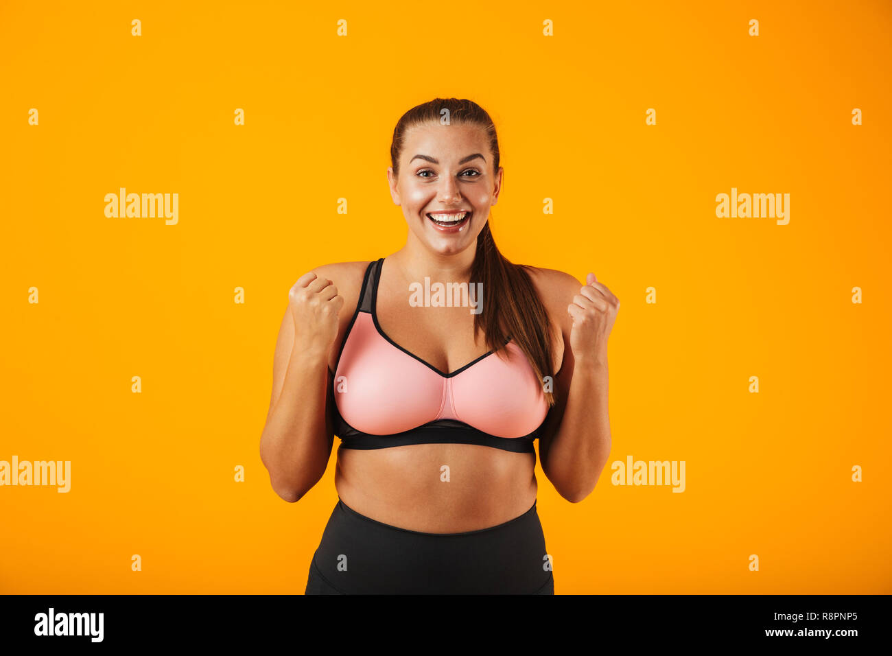 Portrait of happy chubby woman in sportive bra smiling and
