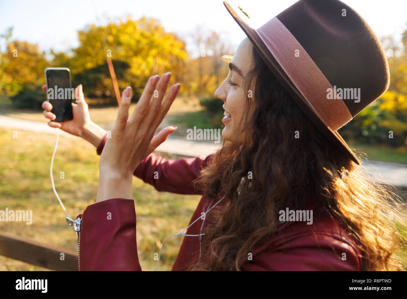 Image of a beautiful woman sitting walking in park using mobile phone ...