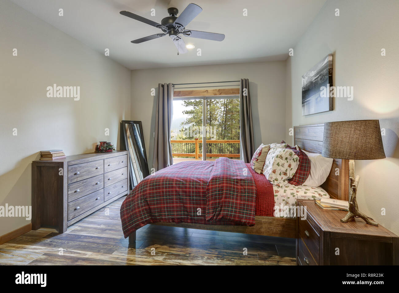 Restful country bedroom furnished with wooden master bed, dark gray dresser  and view of spacious deck Stock Photo - Alamy, image size:1300x956
