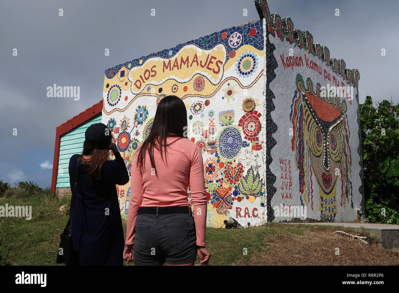 Filipino women view a mosaic mural with phrase 
