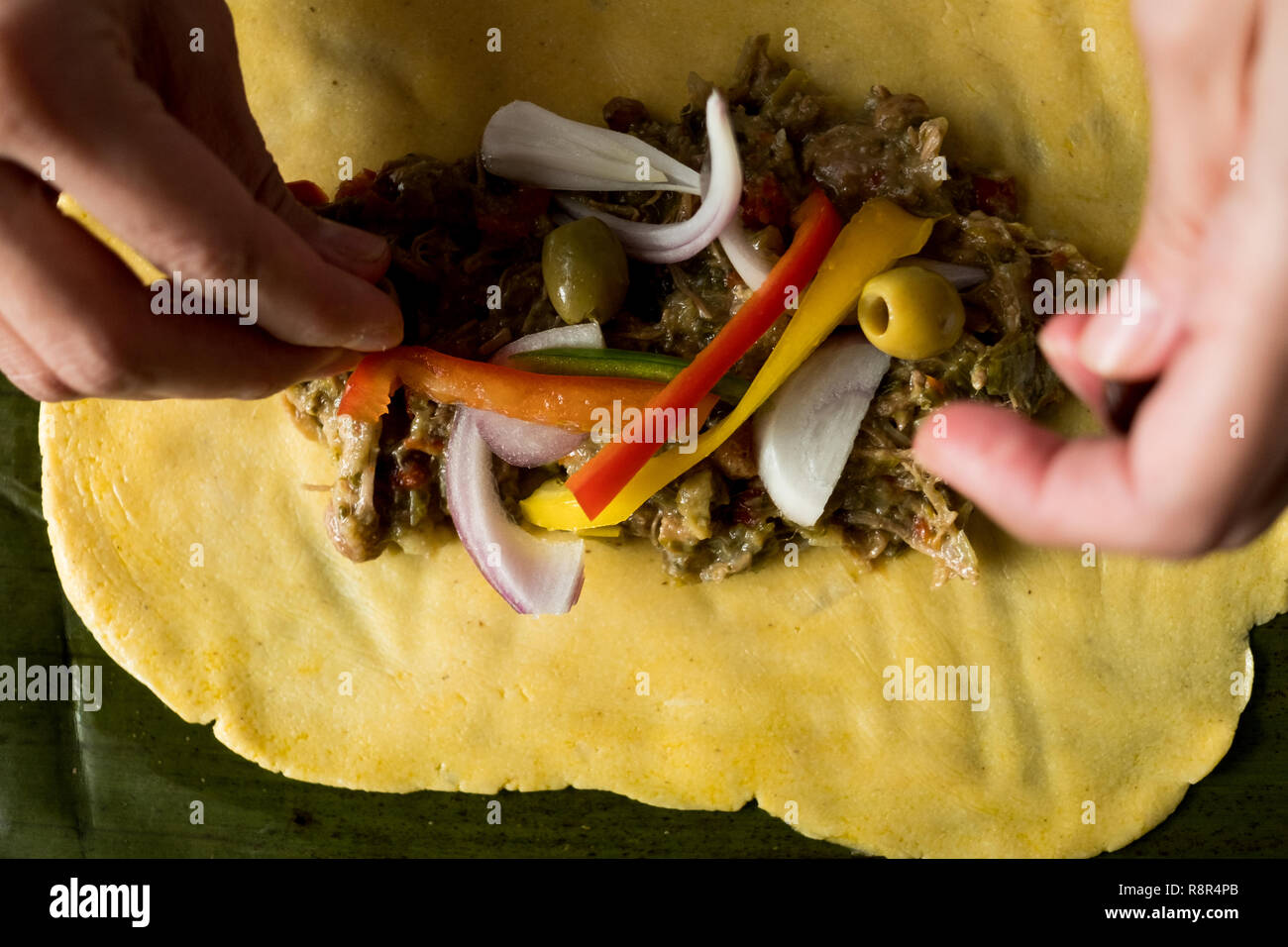 hands of young woman making venezuelan christmas dish hallacas with all ingredients on table Stock Photo