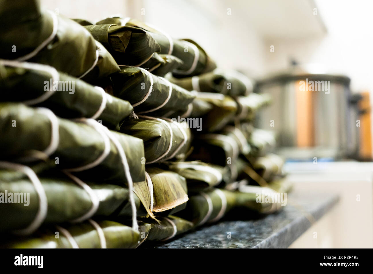 stack of traditional venezuelan hallacas in kitchen before cooking with pot on fire and boilig water Stock Photo