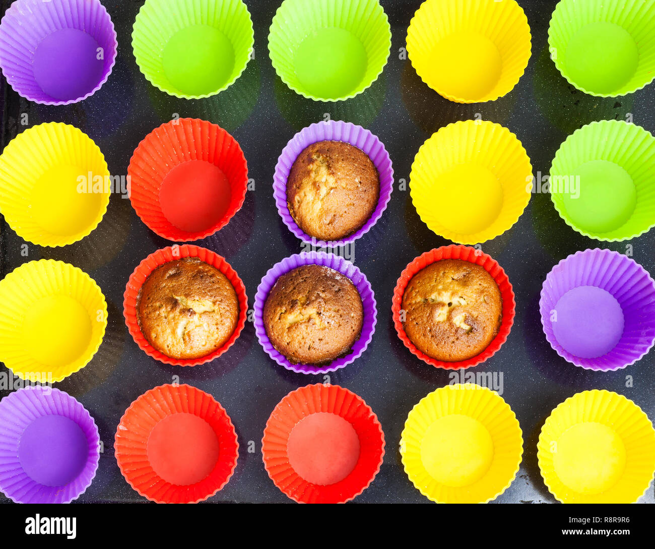 Top View Of Four Baked Cupcakes And Many Empty Multicolored Silicone Molds On Dark Tray Top View Of Four Baked Cupcakes And Many Empty Multicolored Silicone Molds On Dark Tray