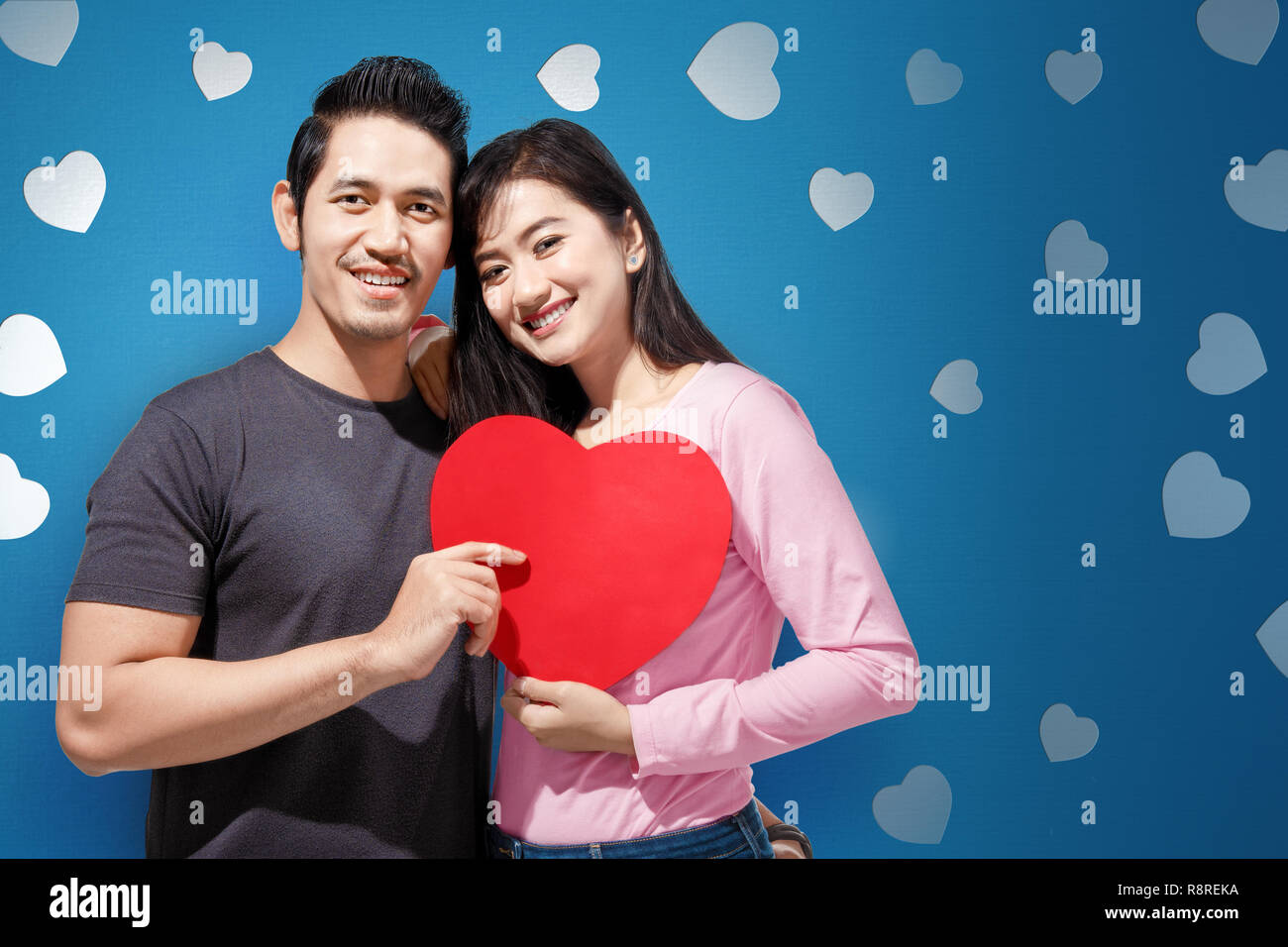 Happy asian couple hugging and holding red heart shape together. Love ...