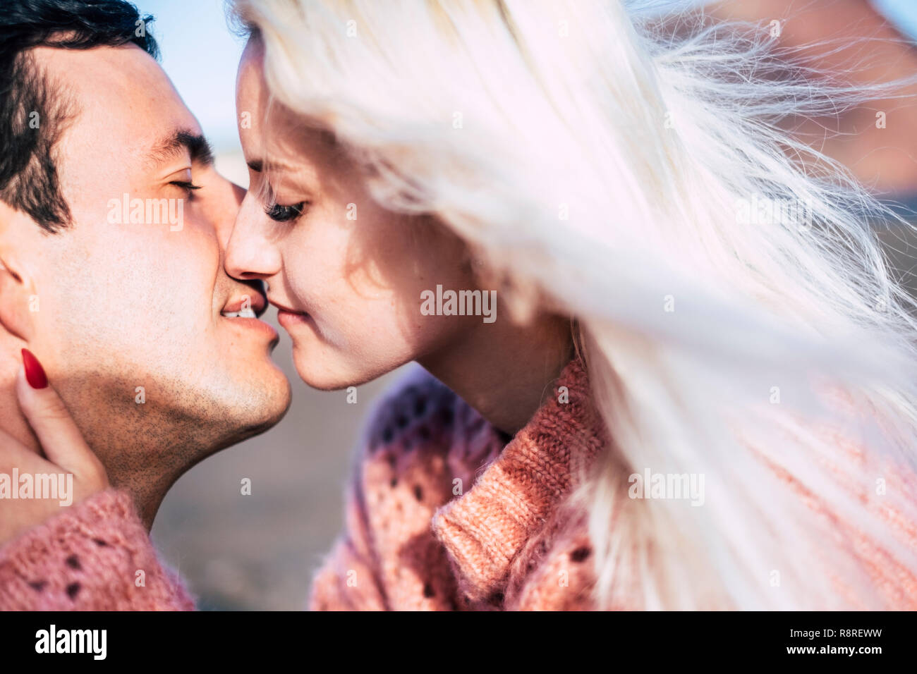 closeup portrait of young beautiful attractive caucasian couple kissing under the sun in outdoor space - love and kiss young people millennial concept Stock Photo