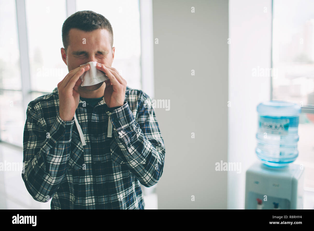 from a young man with handkerchief. Sick guy has runny nose. man makes a cure for the common cold Stock Photo