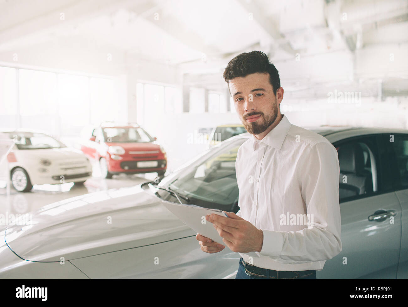 friendly vehicle salesman presenting new cars at showroom. Photo of
