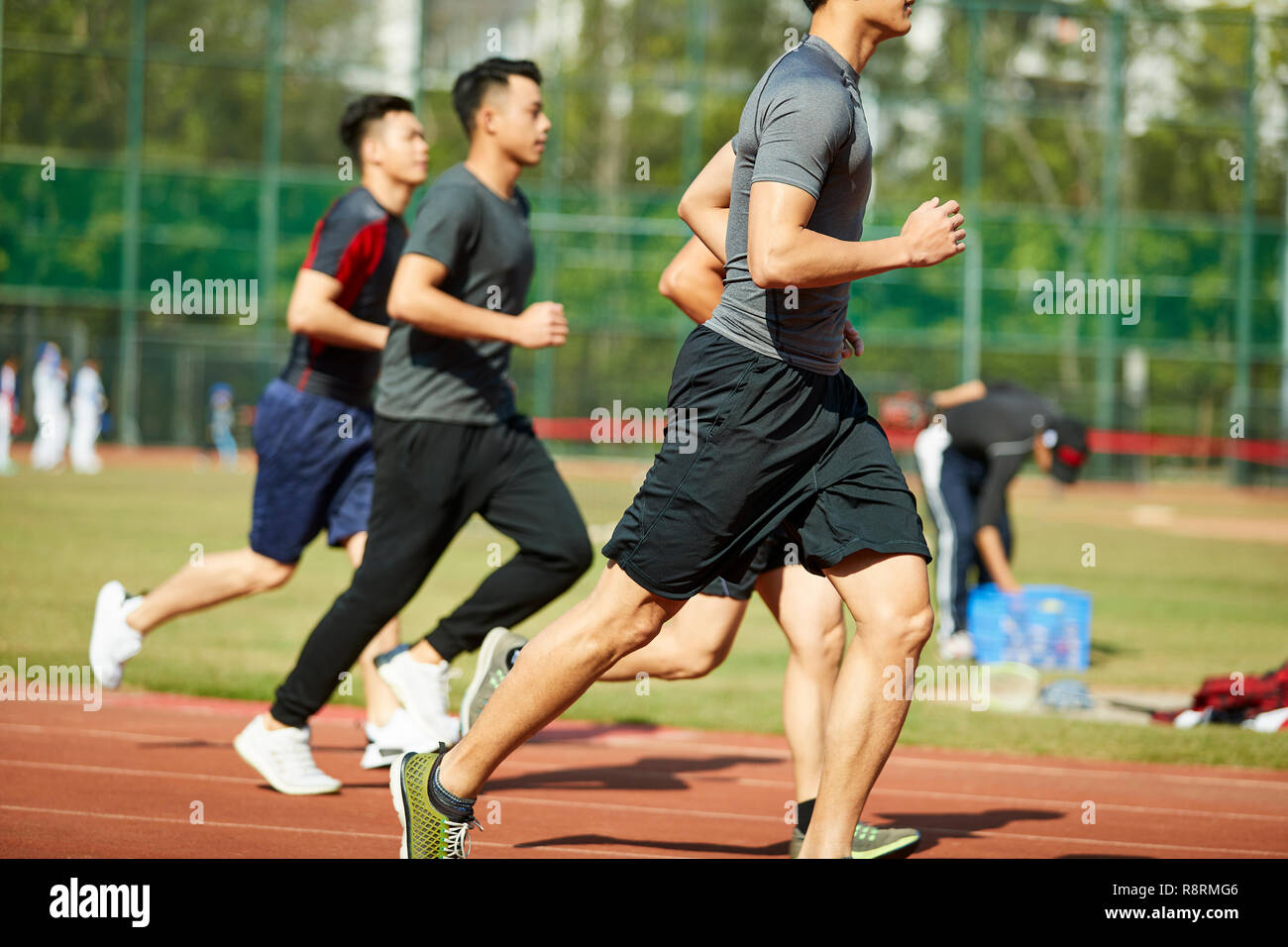four young asian track and field athletes racing competing against each other. Stock Photo