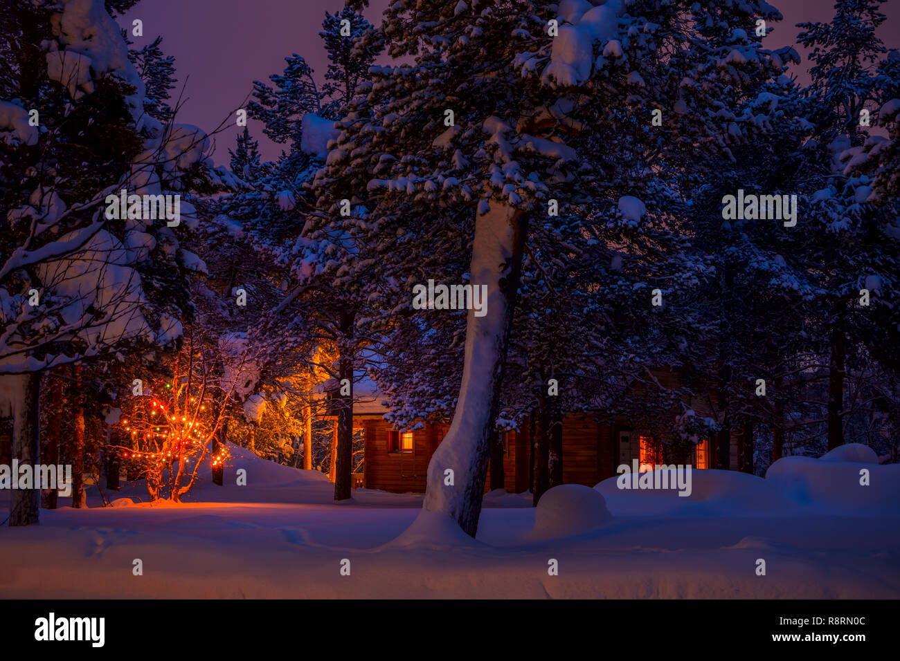 Finnish Lapland. Cottage in the night winter forest and Christmas garland. A lot of snow Stock Photo
