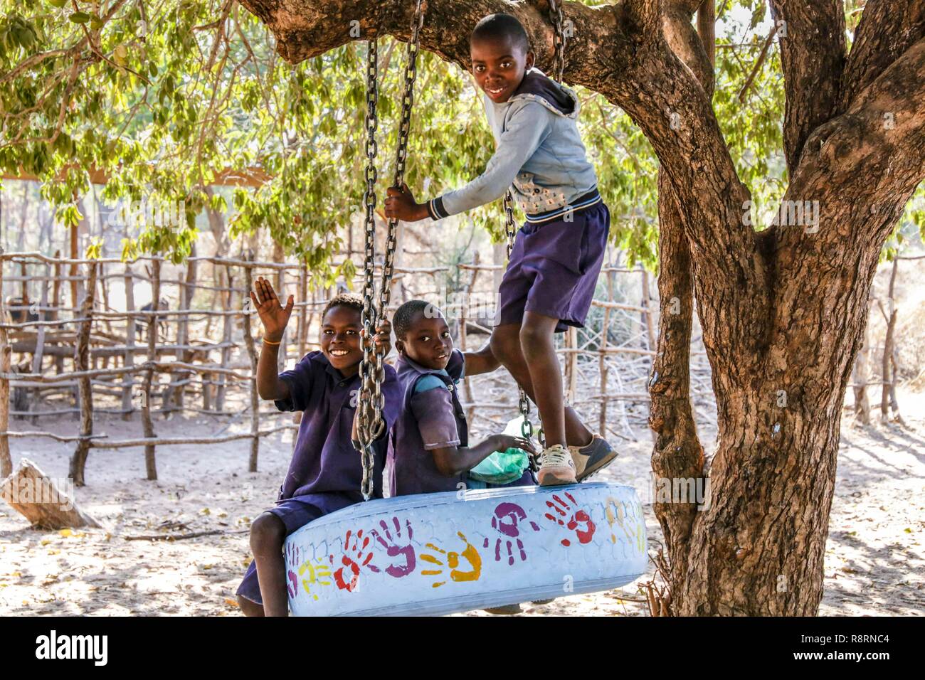 African schoolboys on tyre swing smiling, Kariba South Primary School, Zambia Stock Photo
